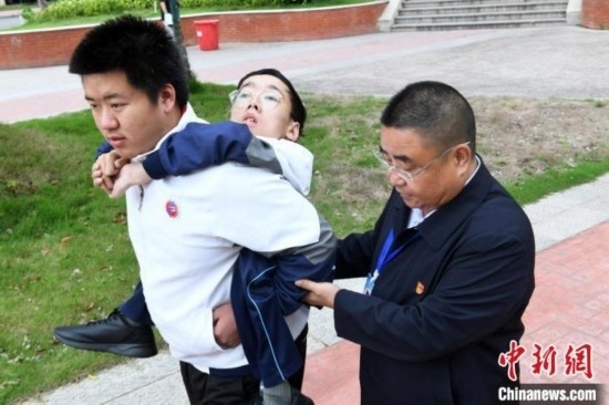 朱金祥背著鐘華強(qiáng)去教室上課的路上，也經(jīng)常碰到值班的校領(lǐng)導(dǎo)和老師前來(lái)搭把手。 卓忠偉 攝