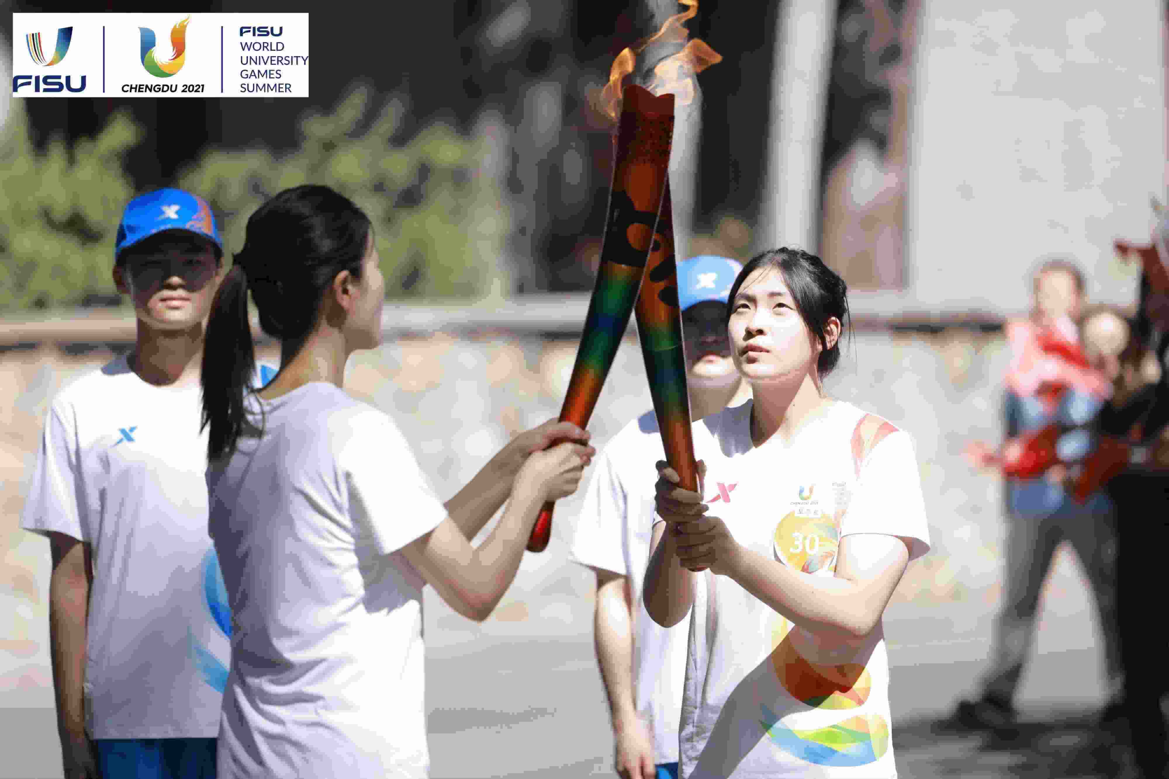 兩名大運會火炬手進行火炬?zhèn)鬟f。 圖片來源：成都大運會執(zhí)委會供圖