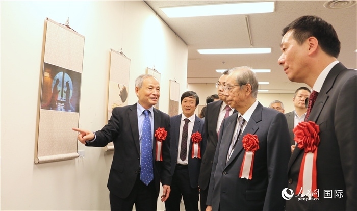 “湖州印象”攝影展主創(chuàng)、世界華人攝影協(xié)會(huì)副會(huì)長(zhǎng)馮學(xué)敏向吳江浩大使、福田康夫前首相等嘉賓介紹展出作品。（人民網(wǎng) 許可攝）