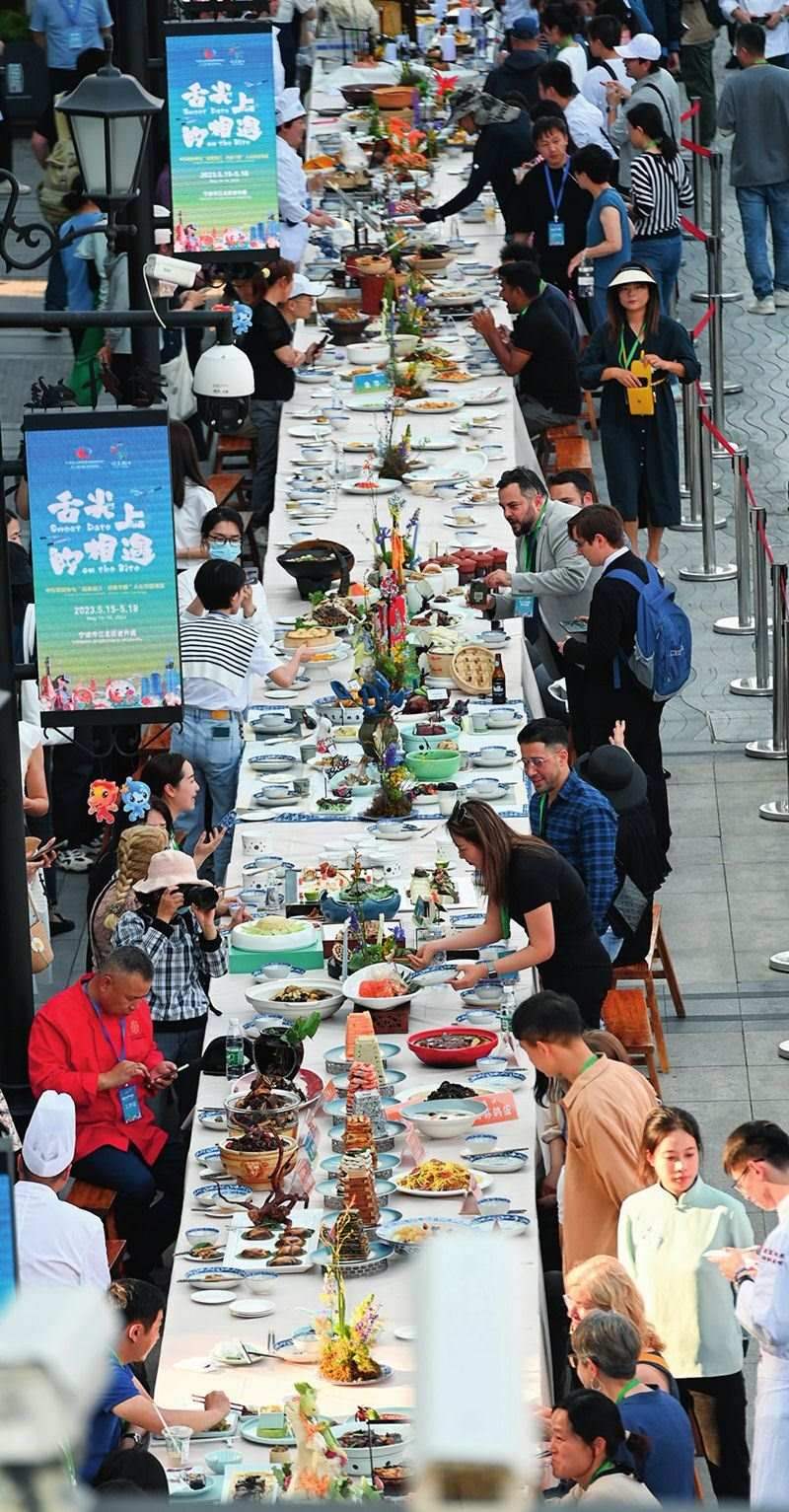 市民和游客在寧波舉辦的第三屆中國(guó)—中東歐國(guó)家博覽會(huì)暨國(guó)際消費(fèi)品博覽會(huì)上品嘗融合中國(guó)和中東歐美食的長(zhǎng)桌宴（2023年5月15日攝）。黃宗治攝/本刊