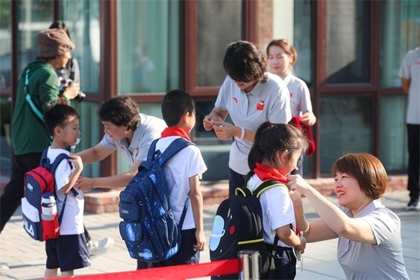8月30日，雄安史家胡同小學(xué)學(xué)生體驗(yàn)學(xué)校生活。老師為學(xué)生佩戴?；?。