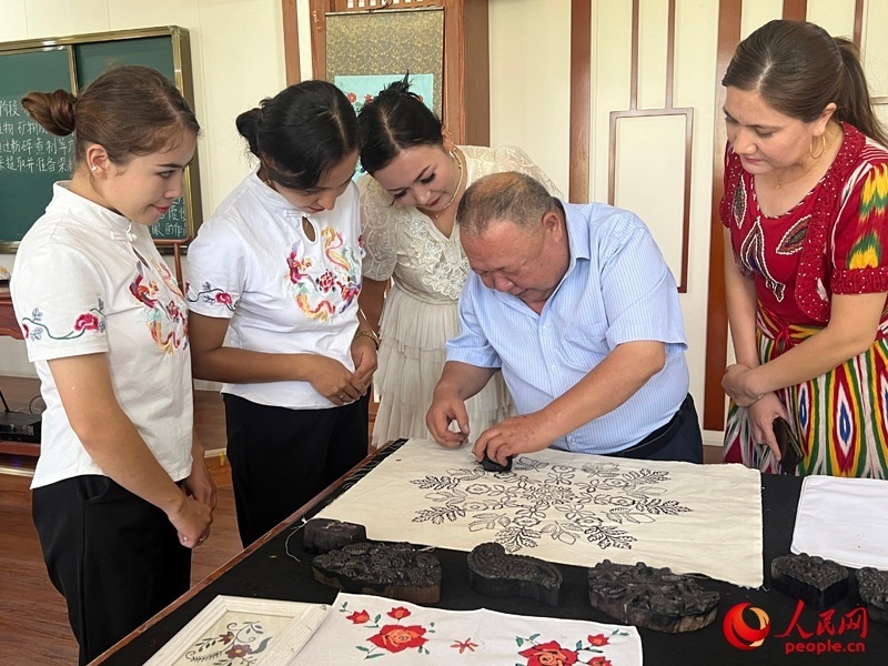 國家級非物質(zhì)文化遺產(chǎn)模戳印花布技藝傳承人吾吉阿西木?吾舒爾展示模戳印花布的制作過程。人民網(wǎng)記者 常雪梅攝
