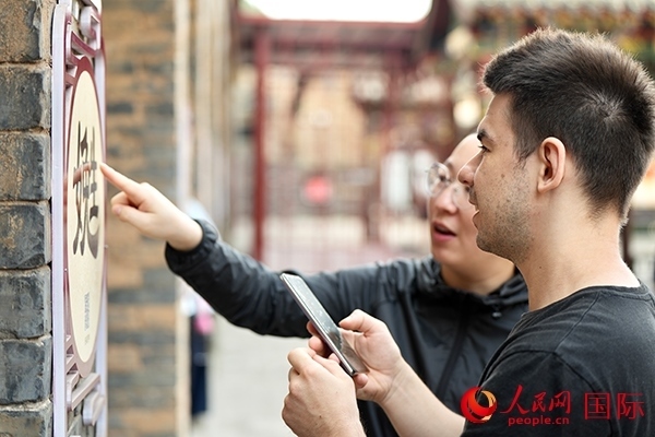 選手安德烈（俄羅斯）在老師指導(dǎo)下學(xué)習(xí)墻壁上張貼的生僻字。人民網(wǎng) 盧鵬宇攝