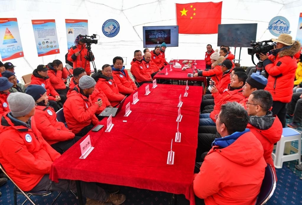 海拔4950米的卓奧友峰科考大本營，科考隊員趙華標(biāo)（手拿麥克風(fēng)看電腦者）在宣讀剛剛接收到的頂峰氣象觀測數(shù)據(jù)，這標(biāo)志著峰頂自動氣象站架設(shè)成功，成功傳回觀測數(shù)據(jù)（10月1日攝）。新華社記者晉美多吉 攝
