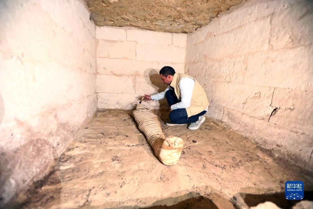 10月15日，在埃及明亞省考古現(xiàn)場(chǎng)，考古人員清理一座石鑿墓中的木乃伊。新華社發(fā)（艾哈邁德·戈馬攝）