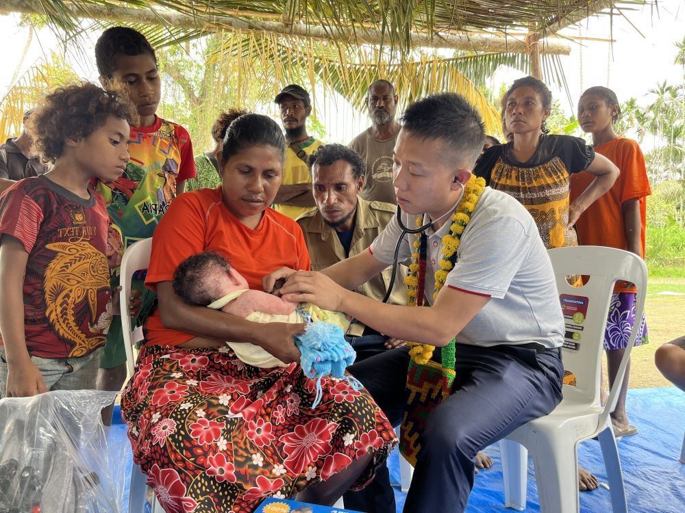 2023年8月5日，在巴布亞新幾內(nèi)亞中央省的一個村莊里，第12批援巴新中國醫(yī)療隊副隊長、新生兒科副主任醫(yī)師劉振球為嬰兒泰樂聽診檢查。泰樂出生時患有重癥，一度生命垂危，經(jīng)過劉振球與當(dāng)?shù)蒯t(yī)護人員的救治最終痊愈。從2002年起，中國連續(xù)向巴新派出12批醫(yī)療隊，為提高巴新醫(yī)療衛(wèi)生水平作出積極貢獻。