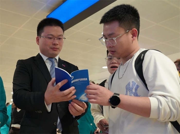 工作人員（左一）在發(fā)放《中國領(lǐng)事保護(hù)與協(xié)助指南》。 中國駐迪拜總領(lǐng)事館供圖