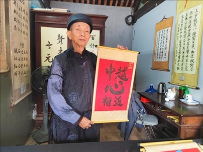 越南首都河內(nèi)文廟內(nèi)，阮明珠展示“中越心相近”書法作品。