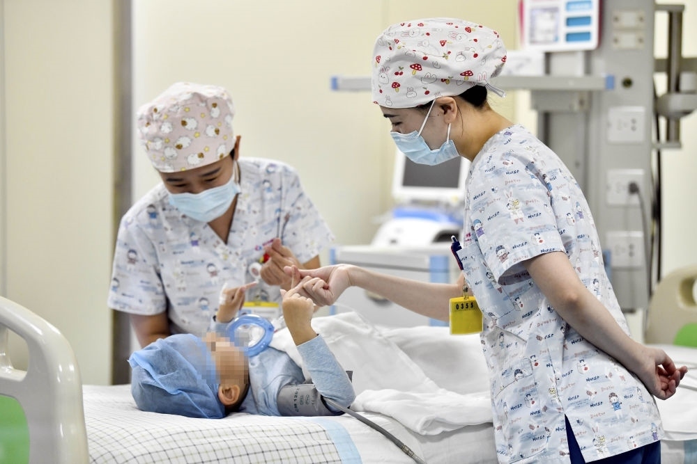 在山東省棗莊市婦幼保健院兒童ICU病房，醫(yī)護(hù)人員為完成靶向治療藥物諾西那生鈉的4歲脊髓性肌萎縮癥患兒加油鼓勁（2022年1月1日攝）。諾西那生鈉注射液是我國首個獲批治療脊髓性肌萎縮癥的進(jìn)口藥物，2019年進(jìn)入中國市場時，每針價格近70萬元。在2021年國家醫(yī)保目錄藥品談判中，以3.3萬元每針的價格進(jìn)入新版醫(yī)保藥品目錄。新華社記者 郭緒雷 攝