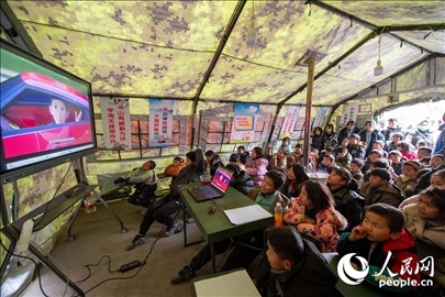 12月22日，在積石山縣大河家鎮(zhèn)大河村安置點(diǎn)，陸軍76集團(tuán)軍某旅搭建的“臨時(shí)學(xué)?！眱?nèi)，小朋友正在看動(dòng)畫片。人民網(wǎng)記者 翁奇羽攝