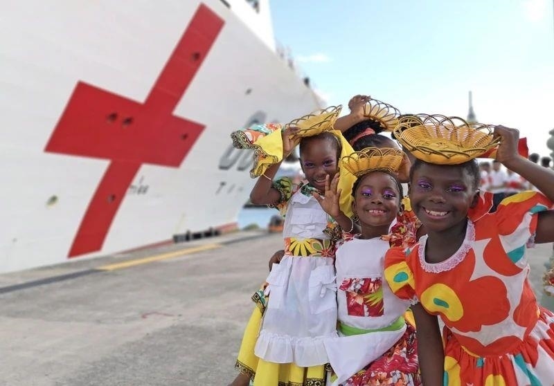 2018年10月，在安提瓜和巴布達首都圣約翰，當?shù)匦∨笥焉泶﹤鹘y(tǒng)服裝歡迎中國海軍“和平方舟”醫(yī)院船首次到訪。