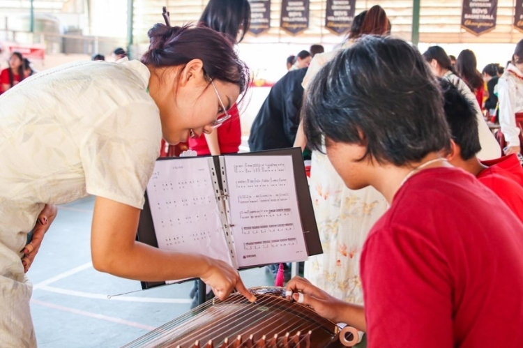 志愿者教師指導(dǎo)學生彈奏古箏?；顒又鬓k方供圖