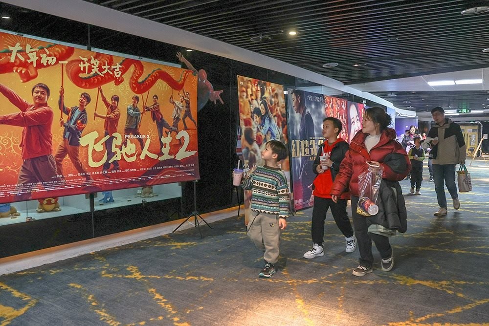 △ 2024年2月16日，在江西贛州一家電影院，觀眾從春節(jié)檔電影的宣傳展板前走過。