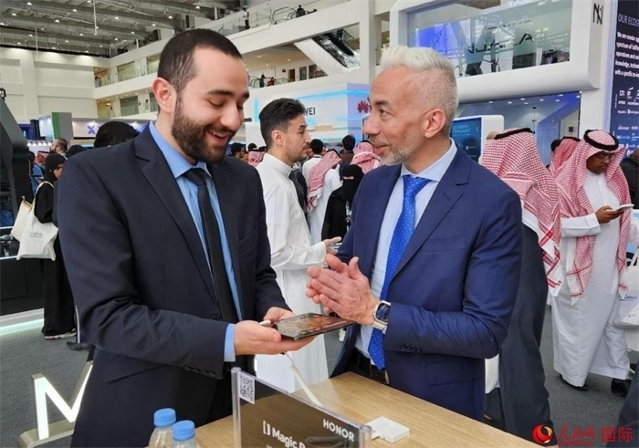 兩名觀眾在榮耀手機展臺前交流。人民網(wǎng)記者 管克江攝