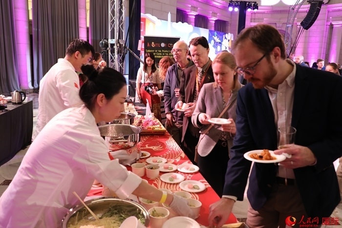 當(dāng)?shù)貢r(shí)間3月7日晚，華盛頓聯(lián)合車站廣場舉行駐美使團(tuán)“使館主廚挑戰(zhàn)賽”。圖為當(dāng)?shù)孛癖娫谥袊古_(tái)前體驗(yàn)中國美食。人民網(wǎng)記者 李志偉攝