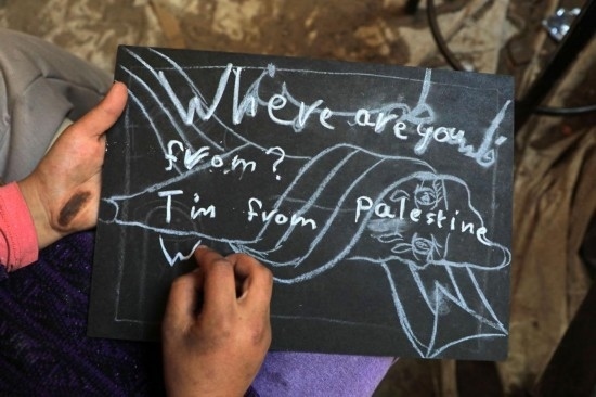 2023年12月28日，一名學(xué)生在加沙地帶南部城市拉法一所學(xué)校的臨時(shí)教室中寫(xiě)下“我來(lái)自巴勒斯坦”的字樣。新華社發(fā)（里澤克·阿卜杜勒賈瓦德攝）