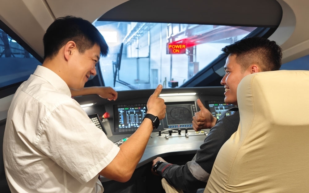 2023年8月25日，在印度尼西亞萬隆的雅萬高鐵德卡魯爾動車所內(nèi)，中國師傅穆振（左）向印尼火車司機塞蒂亞萬講解動車組出庫前的上電作業(yè)。新華社記者 徐欽 攝