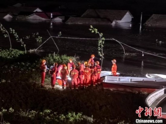  7月6日凌晨3時(shí)，在湖南岳陽(yáng)華容縣團(tuán)洲垸洞庭湖一線堤防，救援人員剛剛完成一次救援任務(wù)，遠(yuǎn)處是被淹的民房。中新社記者 白祖偕 攝