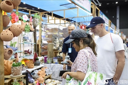 游客在蘭納博覽會特色展位上選購工藝品。人民網(wǎng)記者楊一攝