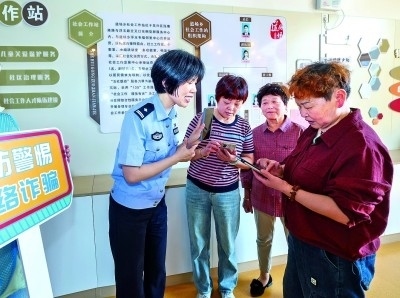 浙江湖州民警指導(dǎo)居民加入湖州“e企安”微信群，實時接收反詐信息。新華社發(fā)