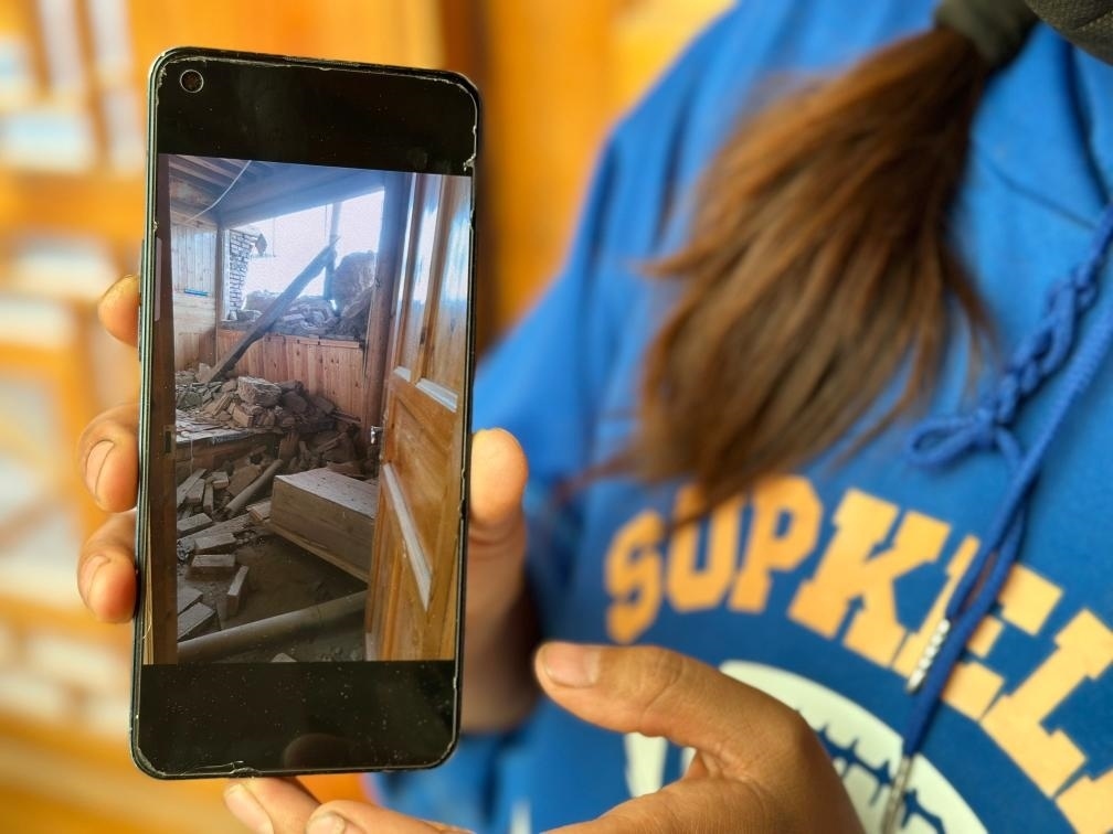 圖為7月17日拉毛東智在手機(jī)上找出地震后房屋受損的照片。新華社記者 張子琪 攝