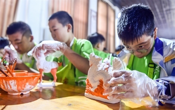小朋友們在洛陽市孟津區(qū)朝陽鎮(zhèn)南石山村體驗唐三彩素胎施釉技藝。圖片來源：視覺中國