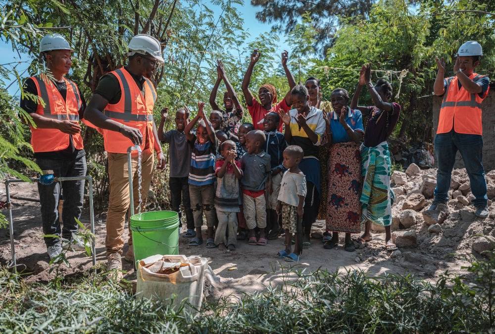 2023年6月13日，在坦桑尼亞姆萬扎省米松圭，工作人員接通水管后贏得當(dāng)?shù)鼐用窆恼茪g呼。新華社記者 王冠森 攝
