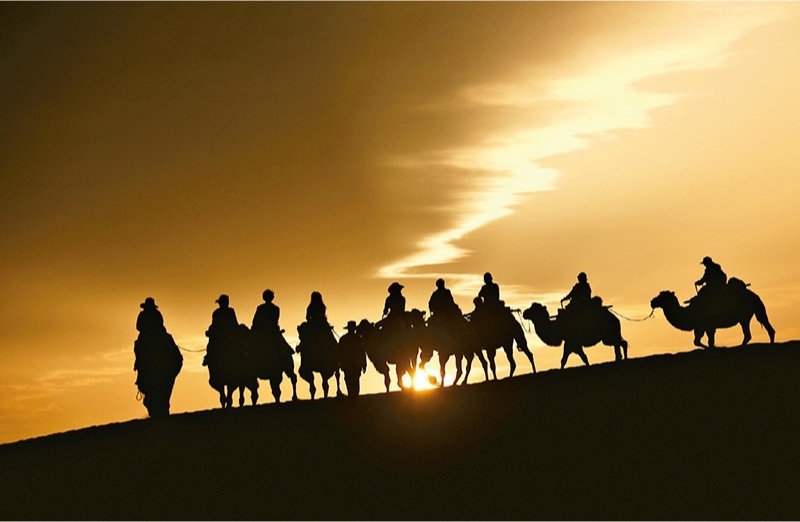 新時代以來，文化和旅游深度融合發(fā)展體制機制不斷健全，成功走出了一條獨具特色的中國旅游發(fā)展之路。圖為2024年9月1日清晨，游客在甘肅省敦煌市鳴沙山月牙泉景區(qū)乘騎駱駝，欣賞大漠風(fēng)光，體驗絲路風(fēng)情。 新華社發(fā) 張曉亮/攝