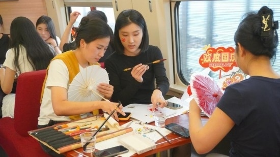 10月1日，旅客們在G1634次列車上給油紙傘作畫。新華社記者周義 攝