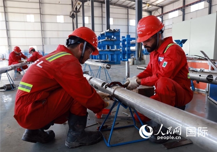 中伊員工共同在檢修鉆井設(shè)備。人民網(wǎng)記者管克江攝