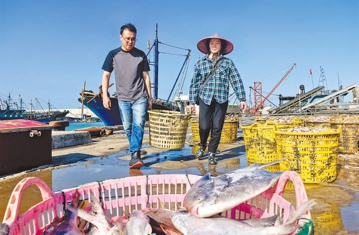 許小斌（左）和漁民一起搬運海鮮。本報記者 付 文攝