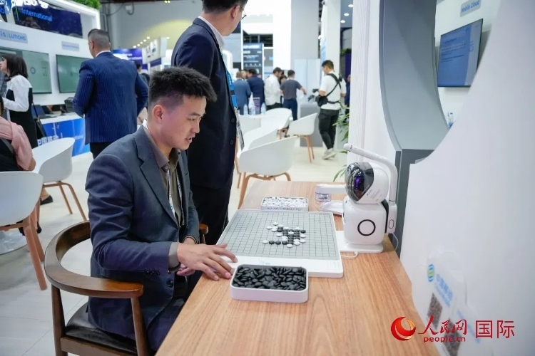 觀眾在中國移動國際有限公司展臺體驗智慧圍棋機器人。人民網(wǎng) 塔里克·易卜拉欣攝