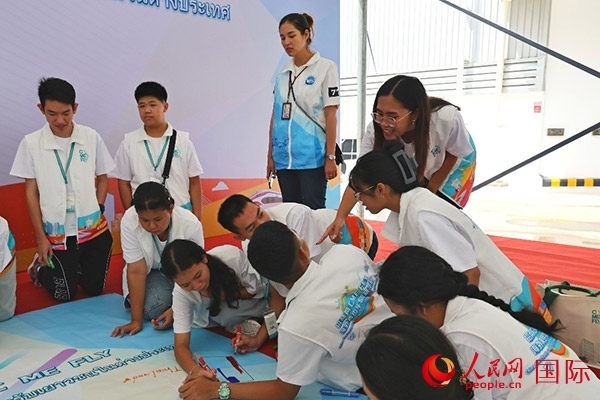 泰國(guó)學(xué)生在開(kāi)營(yíng)儀式展板上繪制圖案。人民網(wǎng)記者 白元琪攝