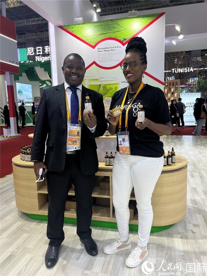 6月6日，布隆迪駐華大使館一等參贊布利馬索·阿爾弗雷德 (左，Bulimaso Alfred) 和參展商卡馬里扎·埃斯特拉 (Kamariza Estella) 在第七屆中國(guó)國(guó)際進(jìn)口博覽會(huì)布隆迪館展示當(dāng)?shù)厣a(chǎn)的辣木油。（人民網(wǎng) 艾里士 攝）