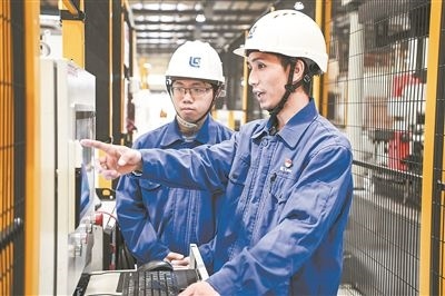 在廣西柳工機(jī)械股份有限公司生產(chǎn)車間內(nèi)，一名高級(jí)技師（右）給徒弟講解數(shù)控設(shè)備操作細(xì)節(jié)。新華社記者 曹祎銘攝