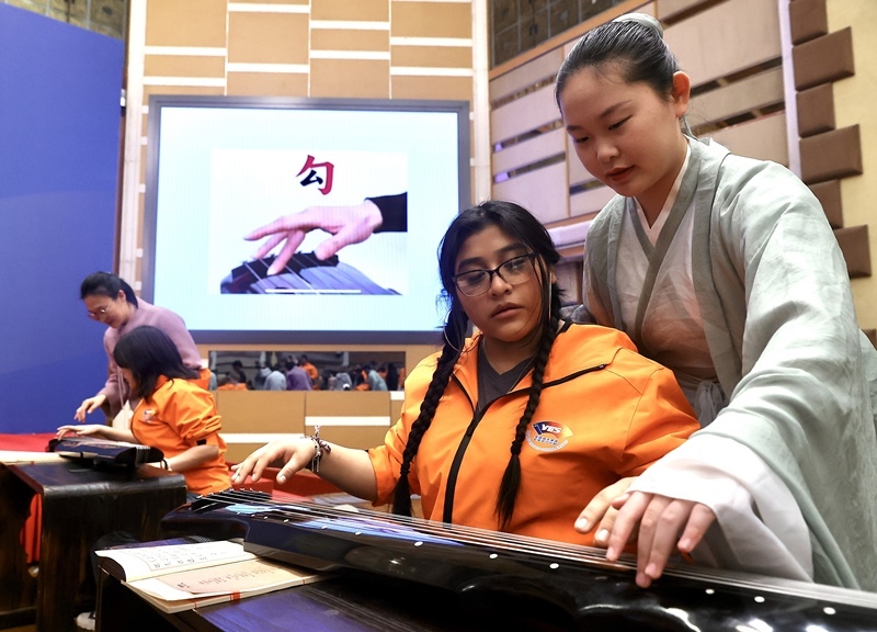 2024年3月20日，美國華盛頓州中學(xué)生代表團(tuán)北京大學(xué)交流活動在北京大學(xué)英杰交流中心舉行。圖為來自華盛頓州的中學(xué)生體驗古琴。