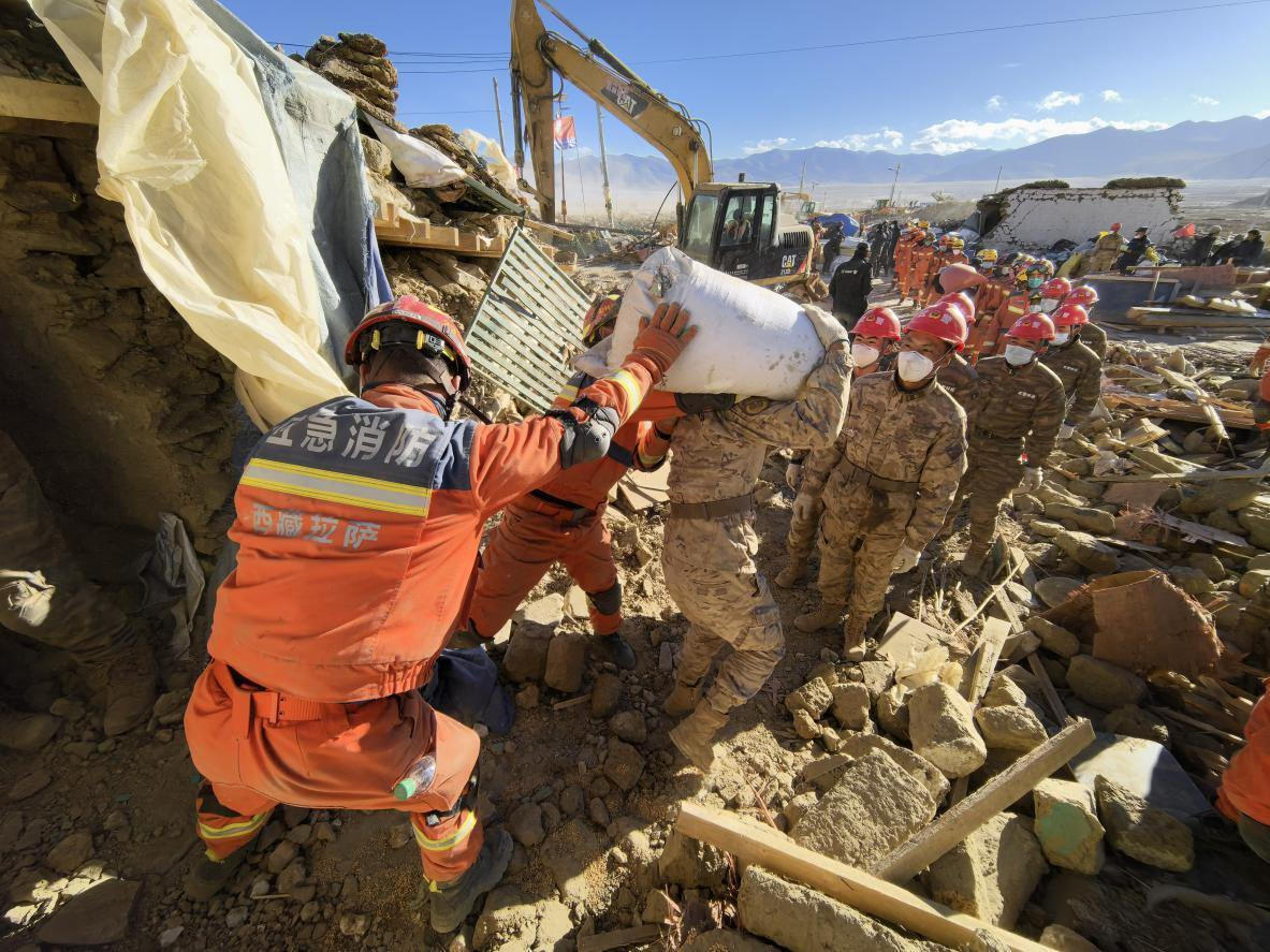 1月11日，定日縣長所鄉(xiāng)古榮村，應(yīng)急消防等救援人員排隊接力搶運掩埋在倒塌房屋下的群眾財物。人民日報記者楊翹楚攝