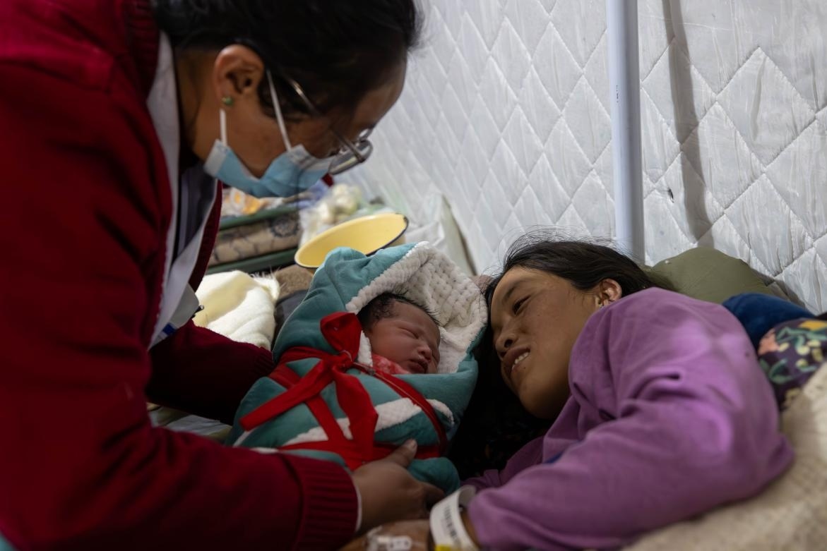 1月10日，定日縣中心醫(yī)院的婦產(chǎn)科醫(yī)生悉心照看一位母親和她懷里的新生兒。人民日報記者張武軍攝