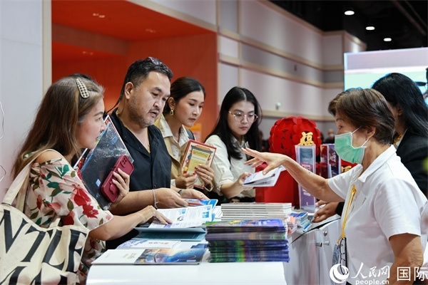外國(guó)觀眾在中國(guó)展臺(tái)仔細(xì)閱讀赴華旅游介紹，向工作人員咨詢關(guān)于中國(guó)美食和景點(diǎn)的詳細(xì)信息。人民網(wǎng)記者 白元琪攝