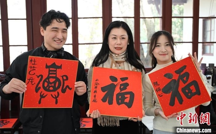 1月20日，外籍留學生和西泠印社社員李硯(中)展示各自創(chuàng)作的福貼。當日，來自巴西、馬來西亞、加納、哈薩克斯坦的外籍留學生在浙江杭州西泠印社體驗福貼、春聯(lián)和篆刻，感受古老的中國傳統(tǒng)文化。中新社記者 王剛 攝