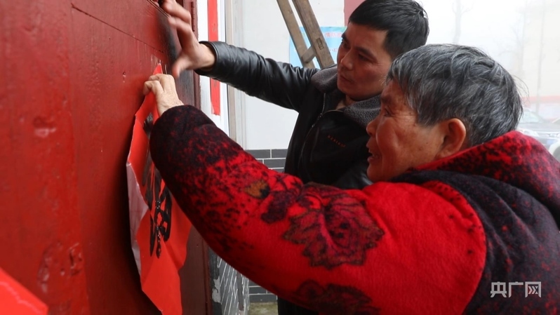 彭德良與70多歲母親貼春聯（央廣網記者 郇康新 攝）