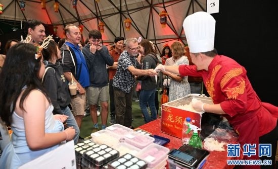 圖為游客在燈節(jié)現(xiàn)場購買小吃。（圖片由奧克蘭中國文化中心提供）