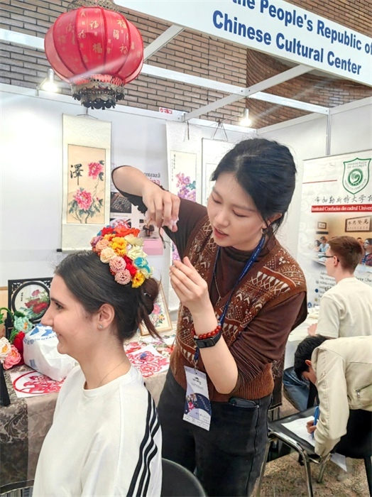 展覽正值羅馬尼亞迎春花節(jié)，國(guó)際中文教師志愿者潘婧穎向游客們介紹了國(guó)家非物質(zhì)文化遺產(chǎn)——福建泉州的簪花文化。布加勒斯特大學(xué)孔子學(xué)院供圖。