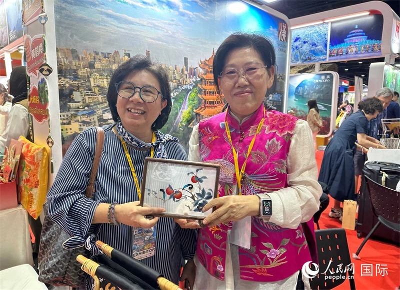 中國“大冶刺繡”傳承人劉小紅（右）參加泰國國際旅游展，向觀眾介紹中國非遺刺繡針法。人民網(wǎng)記者 簡承淵攝
