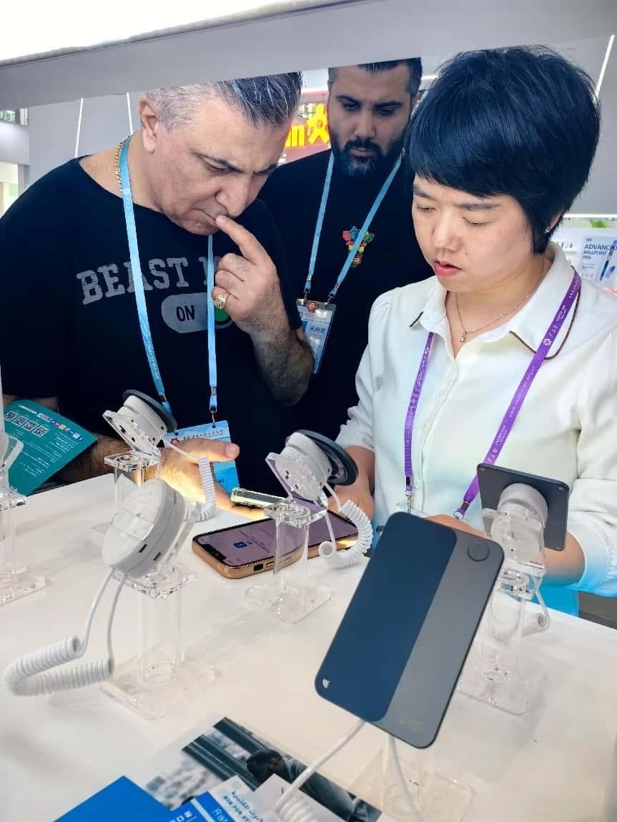 展臺(tái)工作人員向外商展示“AI TOP翻譯終端”。圖片來源：受訪者提供